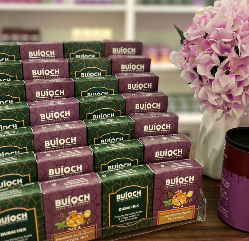 Buíoch chocolate bars and hexes arranged in a retail display beside flowers