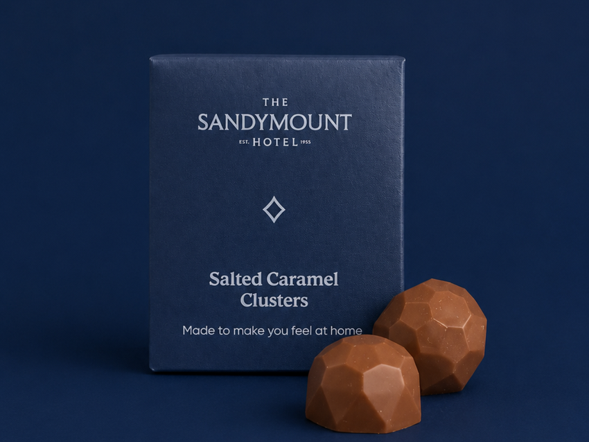 Sandymount Hotel-branded Salted Caramel Clusters pouch beside two milk chocolates