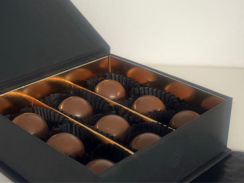 Open black gift box containing an assortment of chocolates
