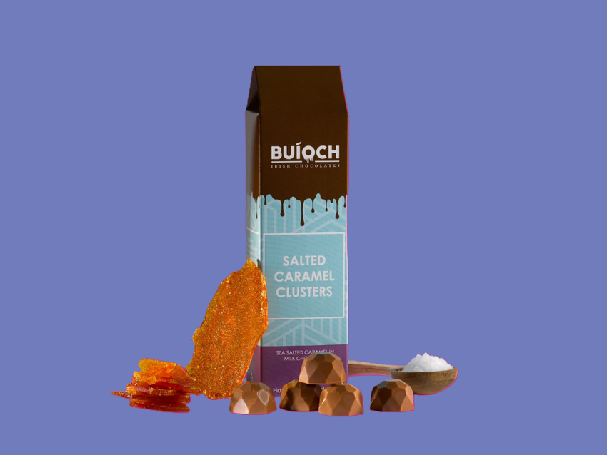Buíoch Salted Caramel Clusters with packaging and ingredients on a blue background