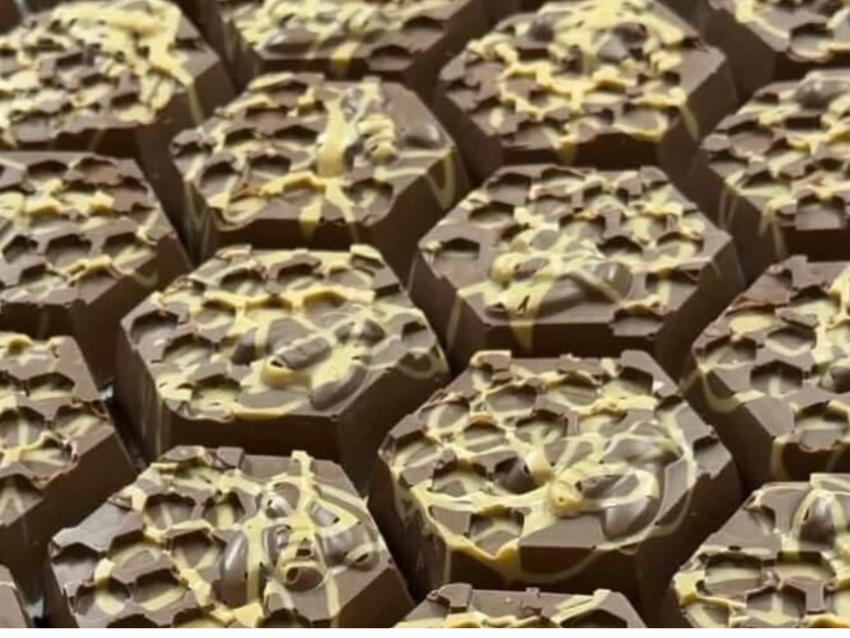 Rows of hexagonal chocolates decorated with pale chocolate drizzle