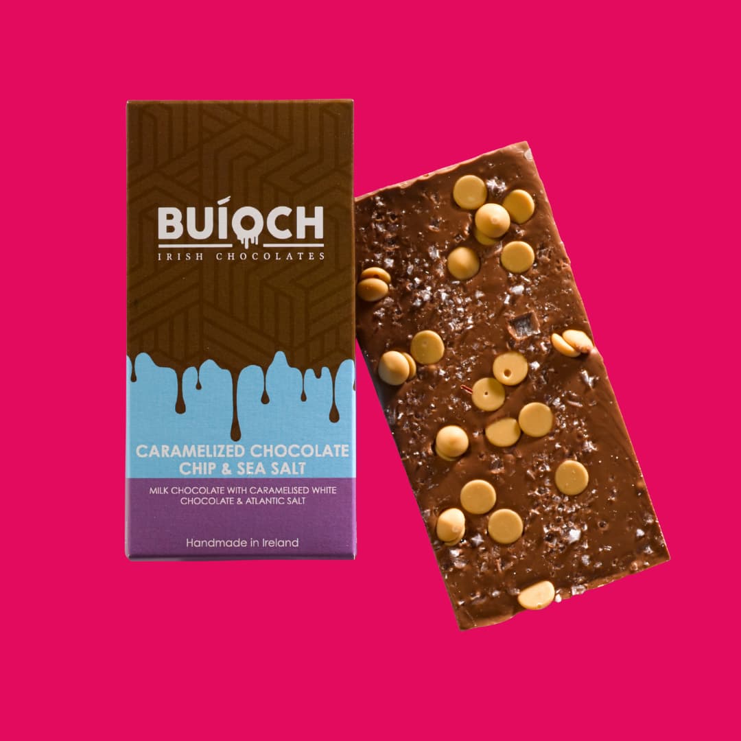 Caramelised Chocolate Chip and Sea Salt Bar - Milk chocolate with flakes of sea salt and caramel chocolate drops. Handmade by Buíoch Irish Chocolates. Packaging on a pink background.