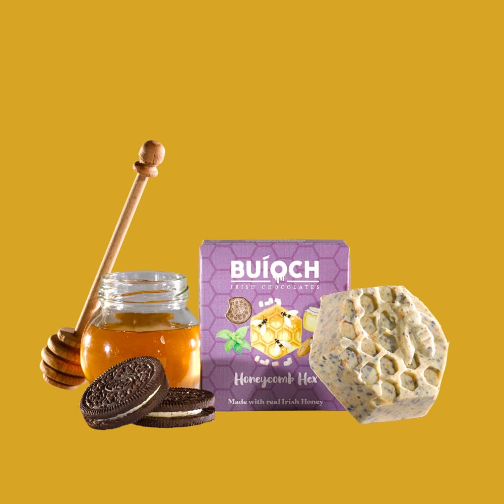 Cookies and Cream White Chocolate Honeycomb Hex - Packaging on a gold background. Handmade by Buíoch Irish Chocolates.