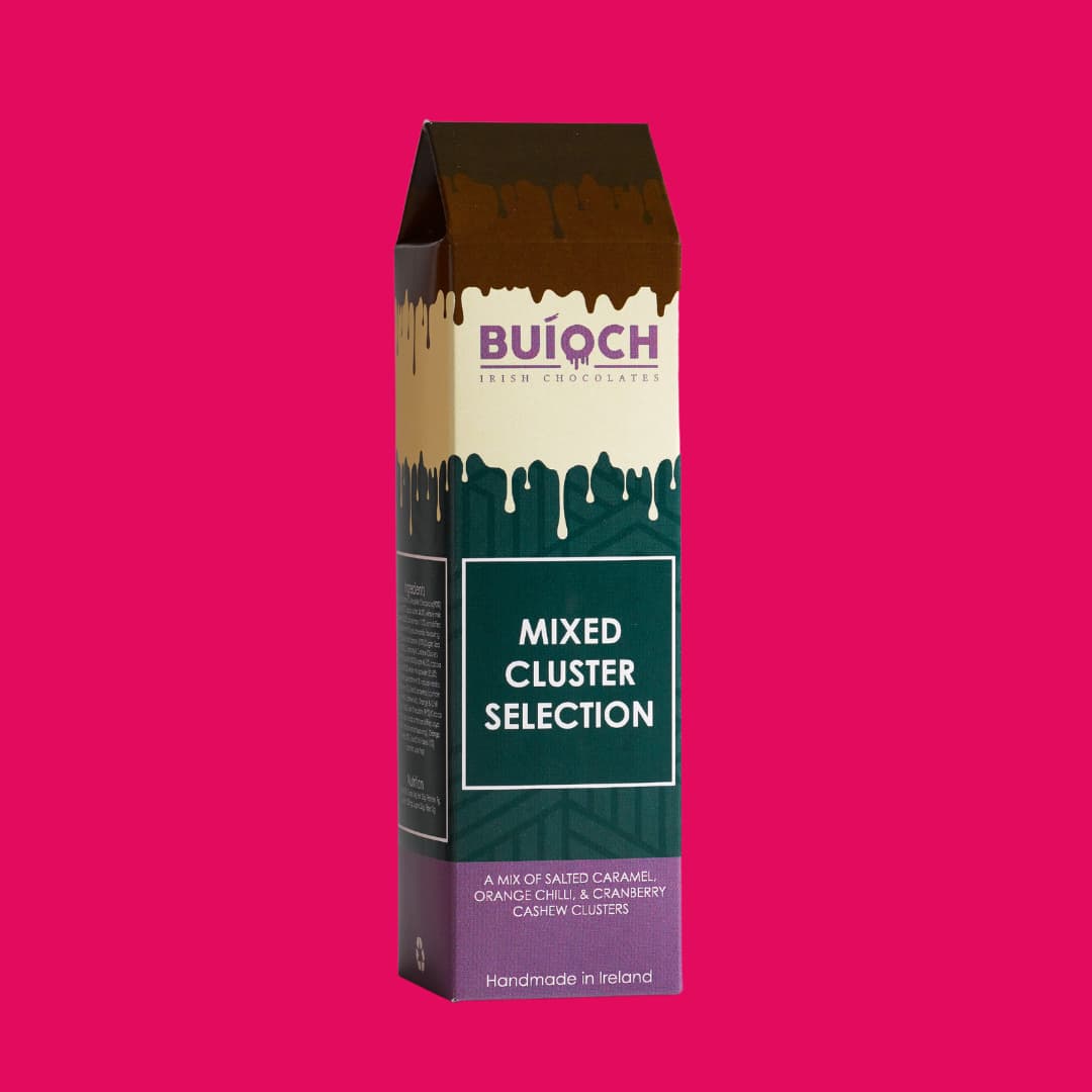 Mixed cluster selection. Milk chocolate salted caramel clusters, white chocolate cranberry cashew clusters and dark chocolate orange and chilli clusters. Handamde by Buíoch Irish Chocolates. Packaging on a pink background