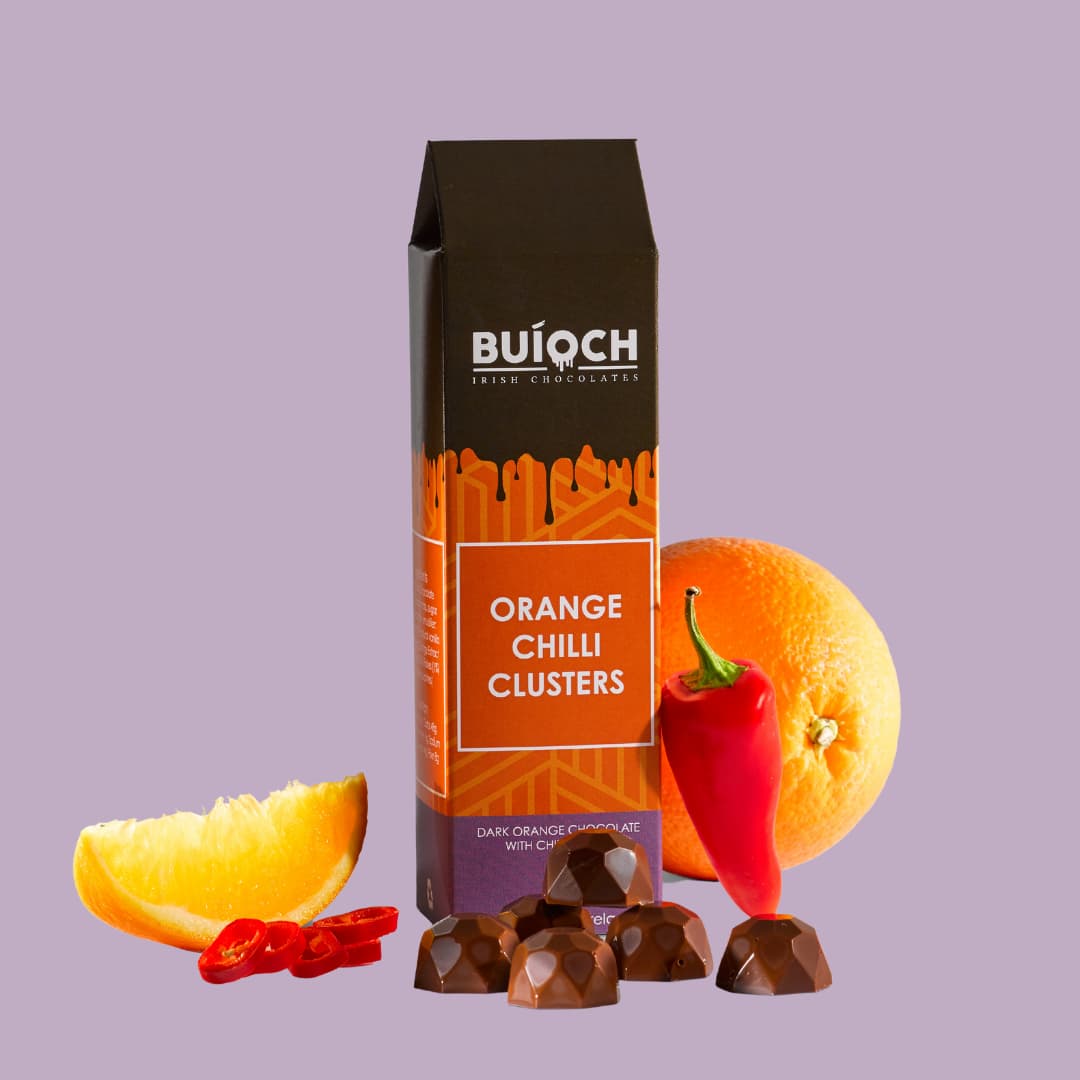 Orange Chilli Clusters - Dark orange chocolate with chilli flakes. Handamde by Buíoch Irish Chocolates. Packaging on a light purple background