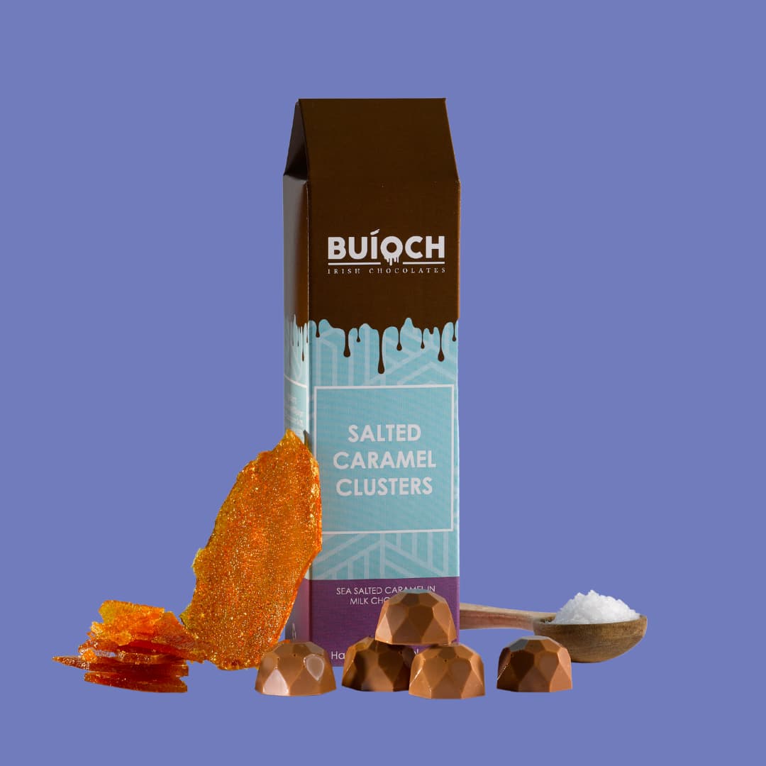 Salted Caramel Clusters - Sea salted caramel in milk chocolate. Handamde by Buíoch Irish Chocolates. Packaging and ingredients on a blue background