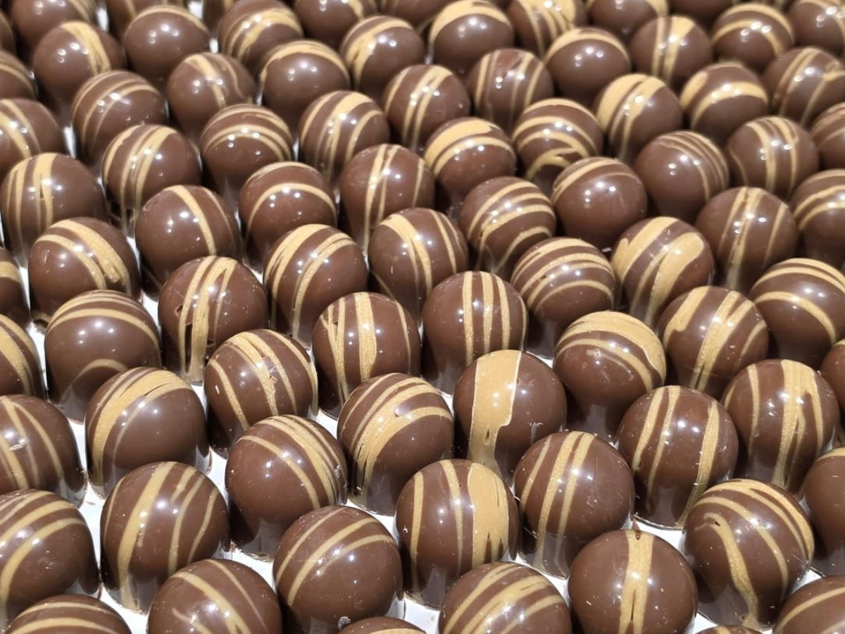 Rows of round chocolate bonbons decorated with pale chocolate stripes