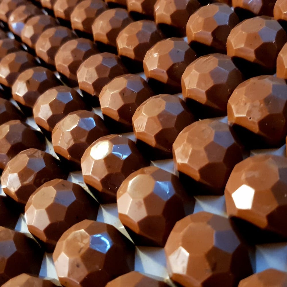 Salted caramel milk chocolate clusters, handmade by buioch Irish chocolates. Laid out as rows and rows of chocolate clusters. 