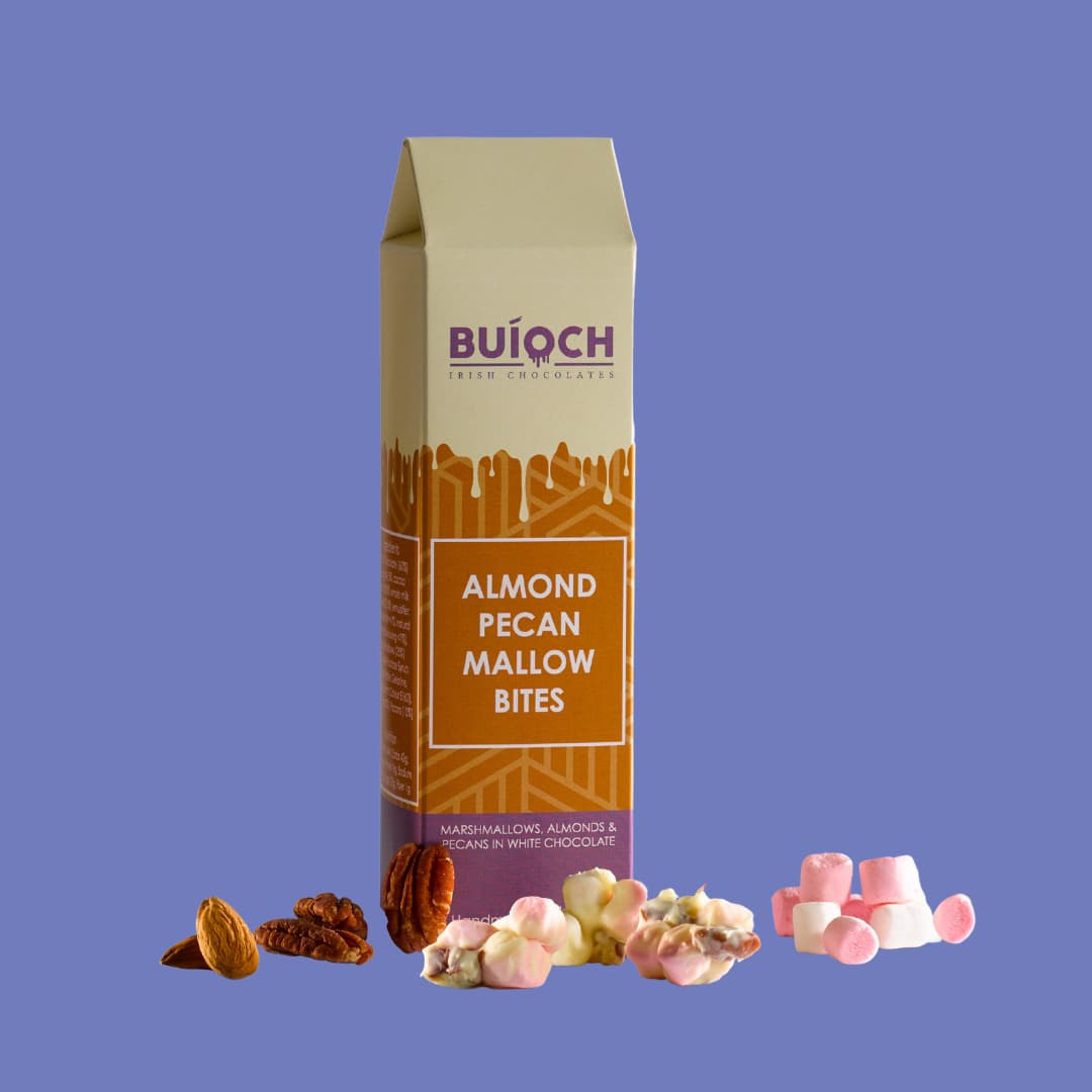 Almond Pecan Mallow Bites - Marshmallows, Almonds and Pecans in White Chocolate. Handamde by Buíoch Irish Chocolates. Packaging, Bites and Ingredients on a Blue Background.