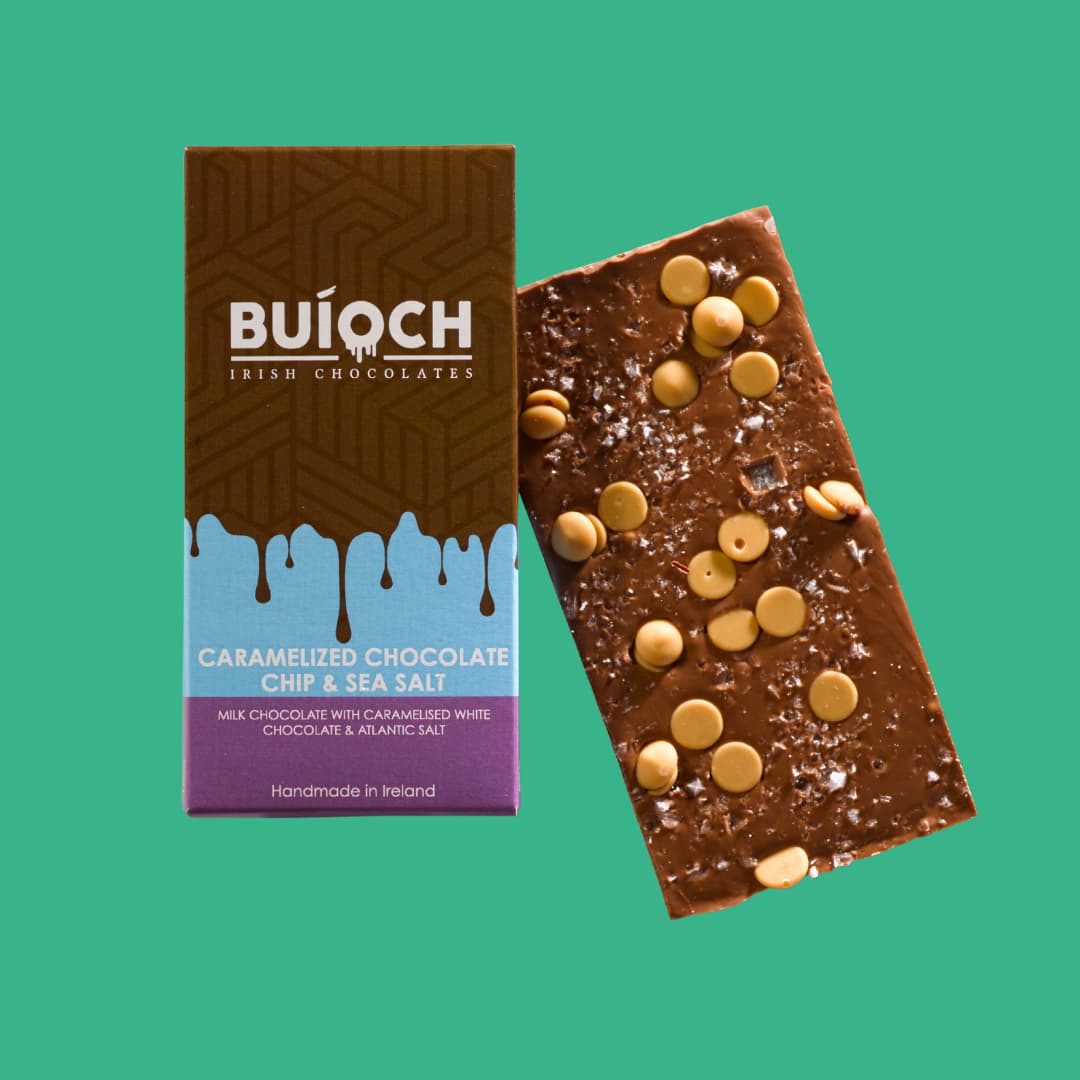 Caramelised Chocolate Chip and Sea Salt Milk Chocolate Bar - Milk Chocolate bar with caramelised white chocolate chips and atlantic sea salt. Handamde by Buíoch Irish Chocolates. Packaging and bar on a mint green background.