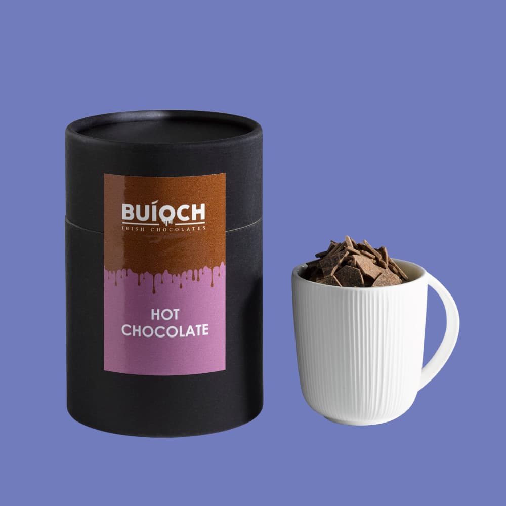 Buioch Hot Chocolate - Chocolate flakes in cup beside packaging on a blue background. Handamde by Buíoch Irish Chocolates.