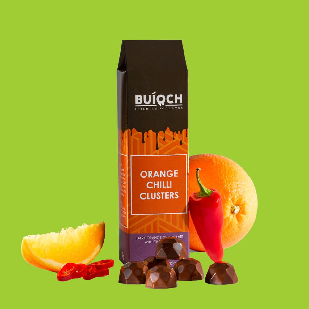 Orange Chilli Clusters - Dark orange chocolate with chilli flakes. Handmade by Buíoch Irish Chocolates. Packaging, clusters and ingredients on a lime green background
