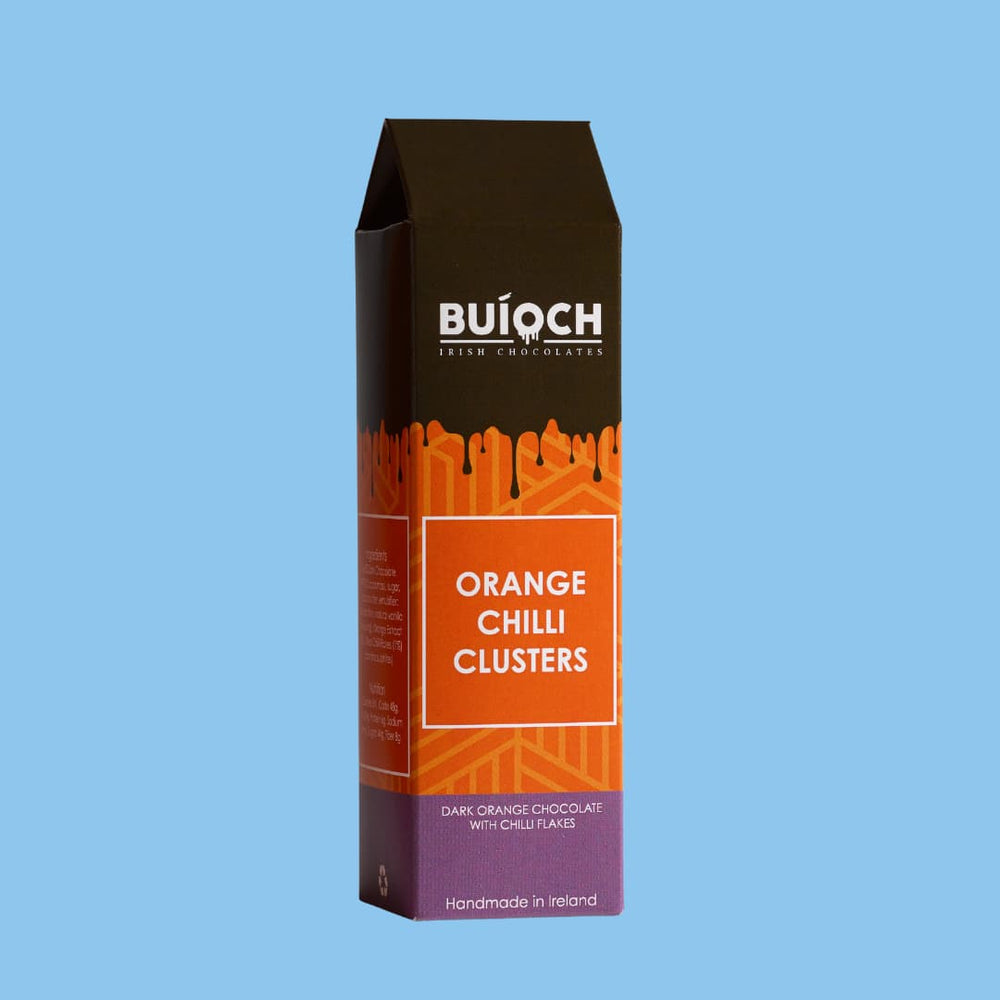 
                  
                    Orange Chilli Clusters - Dark orange chocolate with chilli flakes. Handamde by Buíoch Irish Chocolates. Packaging on a blue background
                  
                