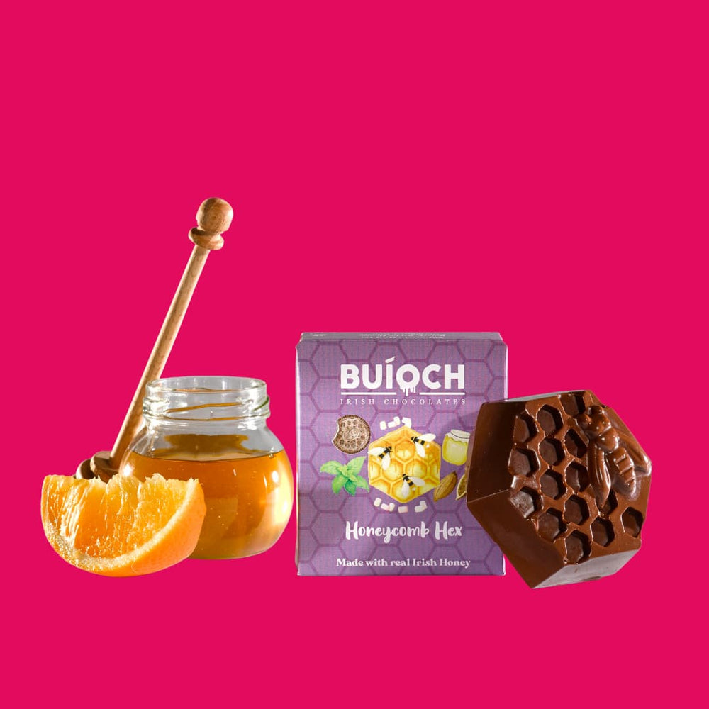 
                  
                    Orange Dark Chocolate Honeycomb Hex - Packaging on a pink background. Handmade by Buíoch Irish Chocolates.
                  
                
