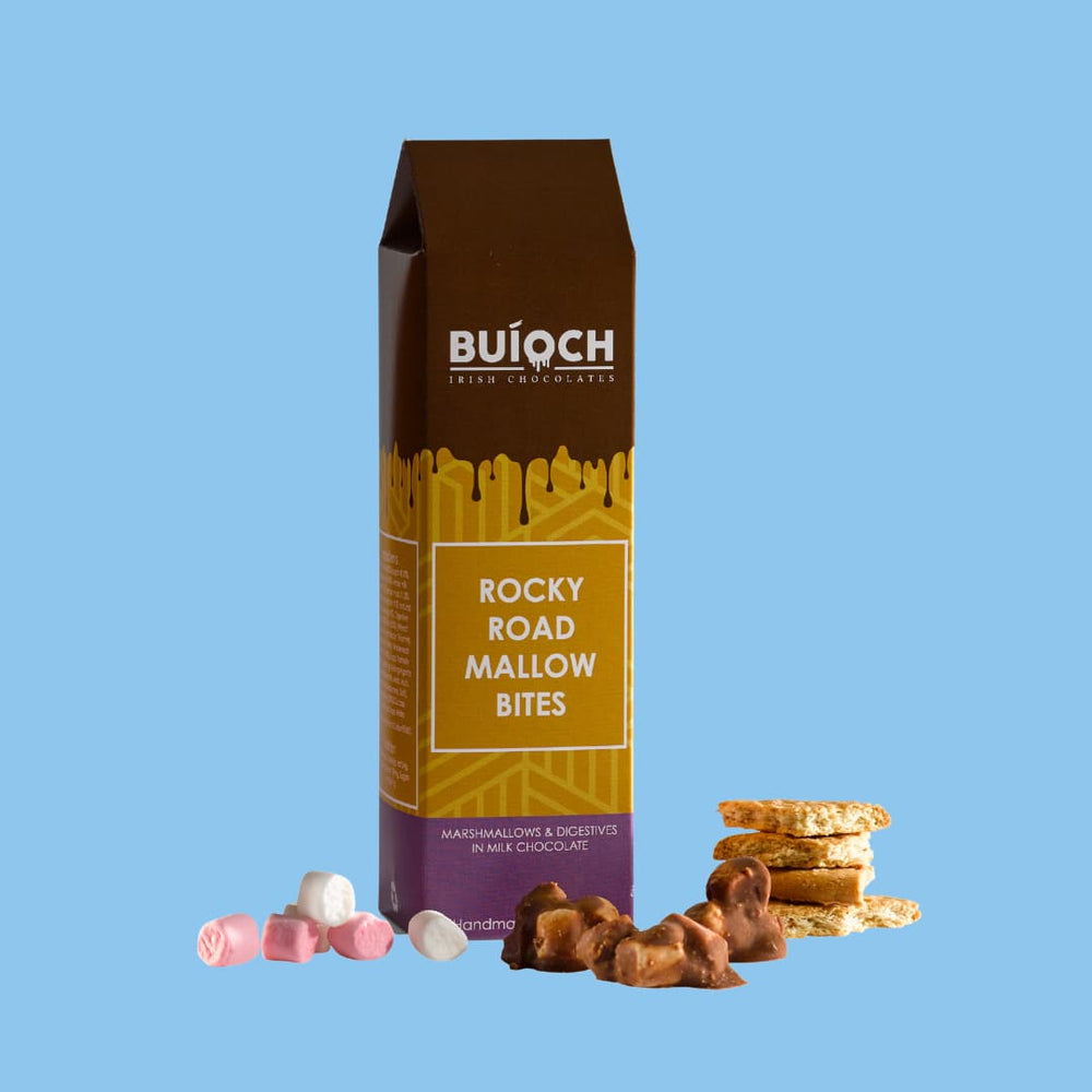 
                  
                    Rocky Road Mallow Bites - Marshmallow and Digestives in Milk Chocolate. Handamde by Buíoch Irish Chocolates. Packaging, Bites and Ingredients on a blue Background.
                  
                